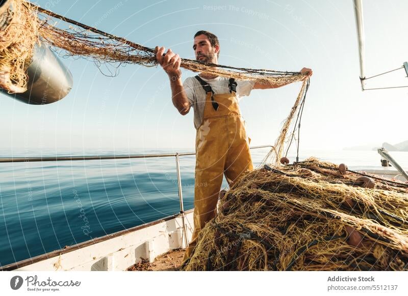 Fisherman fishing in open sea from sail boat fisherman net schooner work uniform male soller balearic islands mallorca seine fish hunt trawler ship yacht