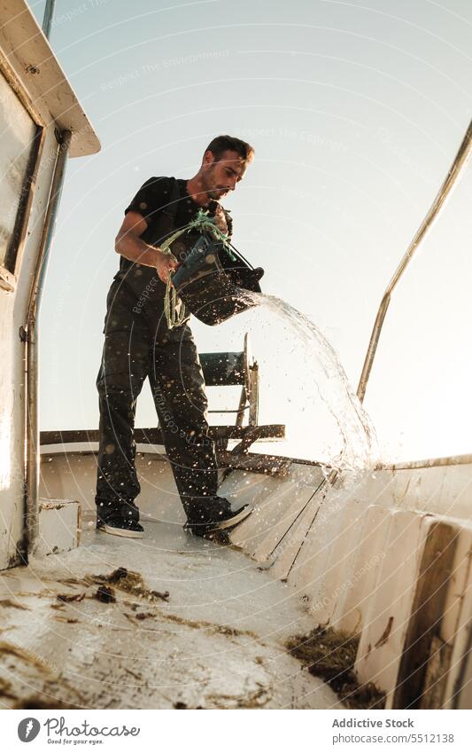 Seaman cleaning deck of fishing boat seaman fisher schooner pour water bucket male soller balearic islands mallorca fisherman sailor tradition seine fish net