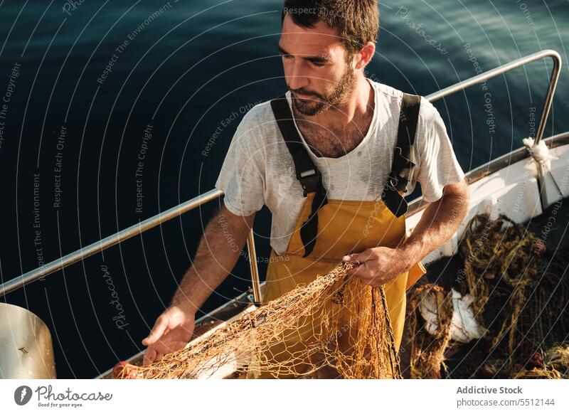 Fisherman fishing in open sea from sail boat fisherman net schooner work uniform focus male soller balearic islands mallorca seine fish hunt trawler