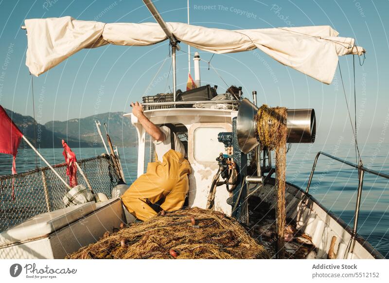 Fisherman working on boat in sea during daytime fisherman fishing equipment marine occupation transport summer float nature tradition water blue sky job