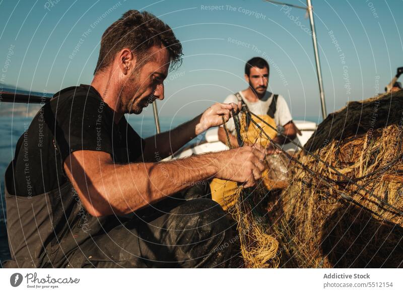 Hispanic men with fishing net sea boat sail summer nature water concentrate male spain soller mallorca ethnic hispanic focus transport ocean marine summertime