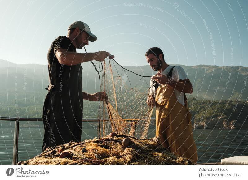 Hispanic men fishing with nets sea water catch equipment summer serious male soller balearic island mallorca nature environment marine aqua hispanic fisherman