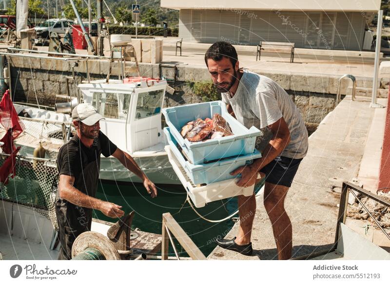 Hispanic men giving and receiving boxes with fish give receive water sea fishing ocean together male soller balearic island mallorca marine hispanic ethnic aqua