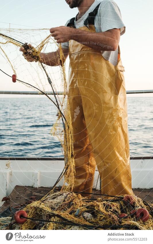 Anonymous fisherman fishing in open sea from sail boat net schooner work uniform focus male soller balearic islands mallorca seine fish hunt trawler