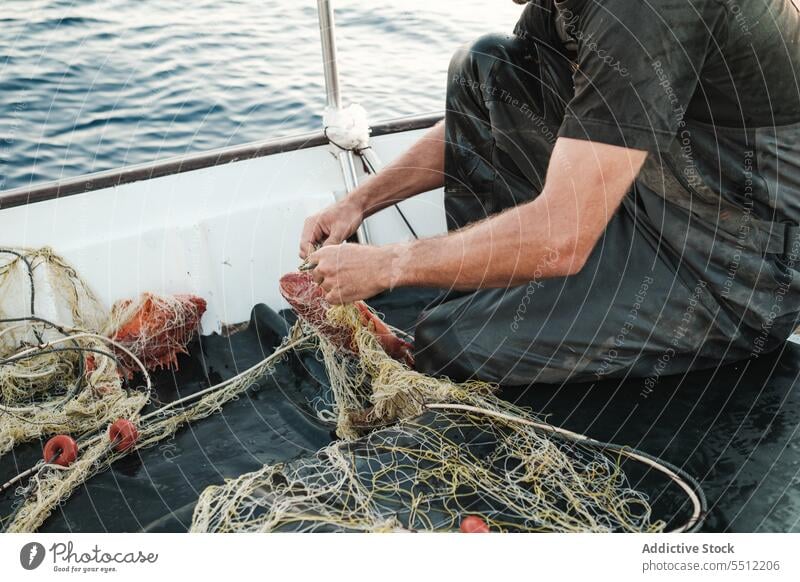 Anonymous man hand untangling fishing net threads to catch fish in daylight fisherman boat water deck equipment nature male transport outside wet aqua summer