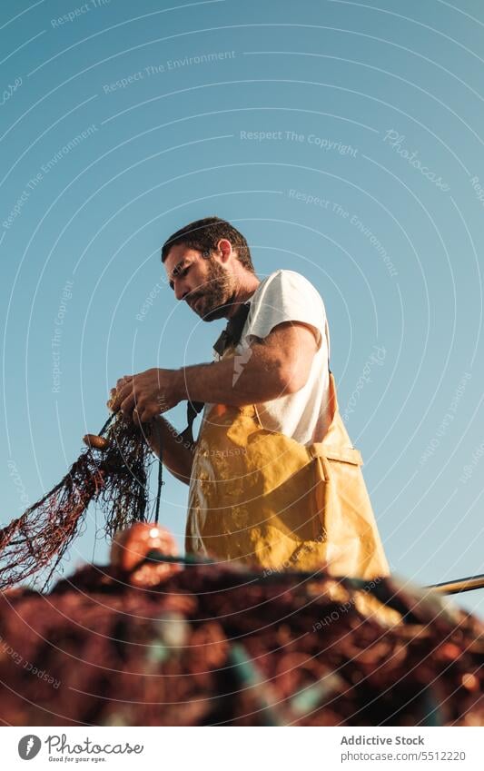 Man pulling net from sail boat in sea man fisher fishing untie trawler apron male fisherman soller balearic islands mallorca seine fish hunt schooner ship yacht