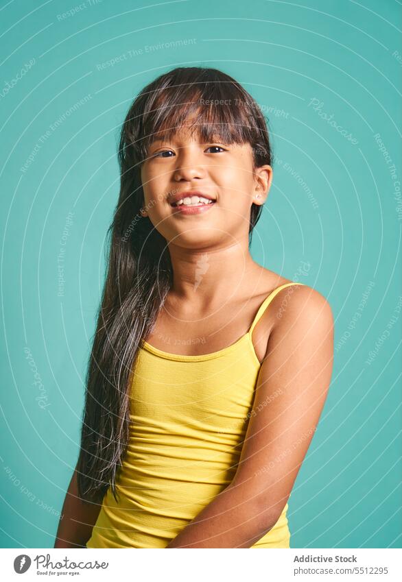 Happy ethnic girl child standing against turquoise backdrop gesture smile kid v sign two fingers happy cute positive joy asian childhood cheerful adorable peace