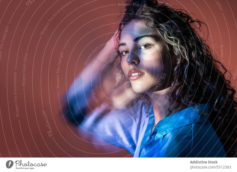 Attractive woman adjusting curly hair in room with lights portrait touch hair fix effect illuminate dot calm peaceful tranquil sensual young female lady