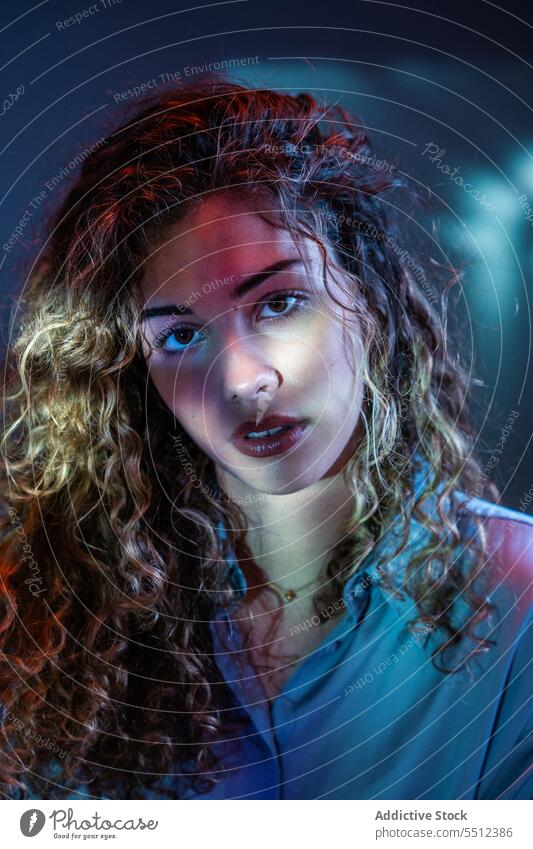 Attractive woman in room with neon lights portrait curly hair effect illuminate dot calm peaceful tranquil sensual young female lady long hair human face dark