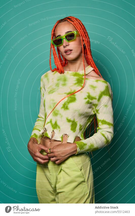 Stylish woman in green outfit and sunglasses confident stylish fashion model studio shot unemotional cool vivid appearance young female afro braids long sleeve