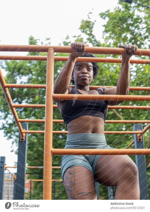 Focused strong young black woman doing exercise on metal bar in open gym sportswoman pull training workout muscular athlete female african american ethnic