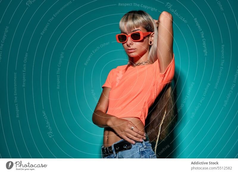 Confident trendy hipster woman in sunglasses hand on head street style posture studio shot informal subculture confident self confident self assured unemotional