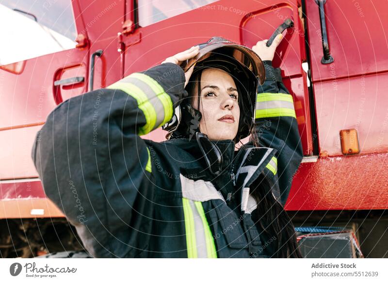 Brave female firefighter getting into fire truck woman prepare adjust helmet profession protect brave young firewoman black hair safety worker risk