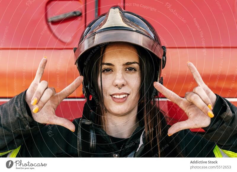 Woman with helmet showing horn sign woman gesture portrait rock and roll safety protect firefighter car female vehicle uniform transport profession professional