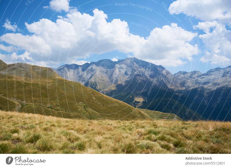 Grassy green hill against mountain terrain under blue sky picturesque pyrenees range landscape nature highland Bachimala grass valley spain scenery cloudy water