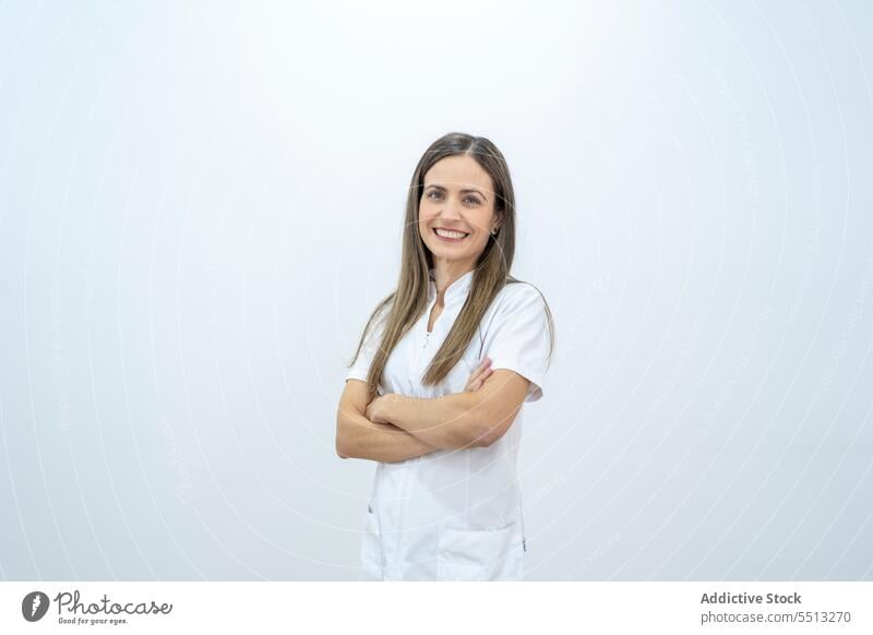 Cheerful woman in medical uniform with arms folded doctor smile hospital clinic arms crossed friendly work professional specialist medicine cheerful job