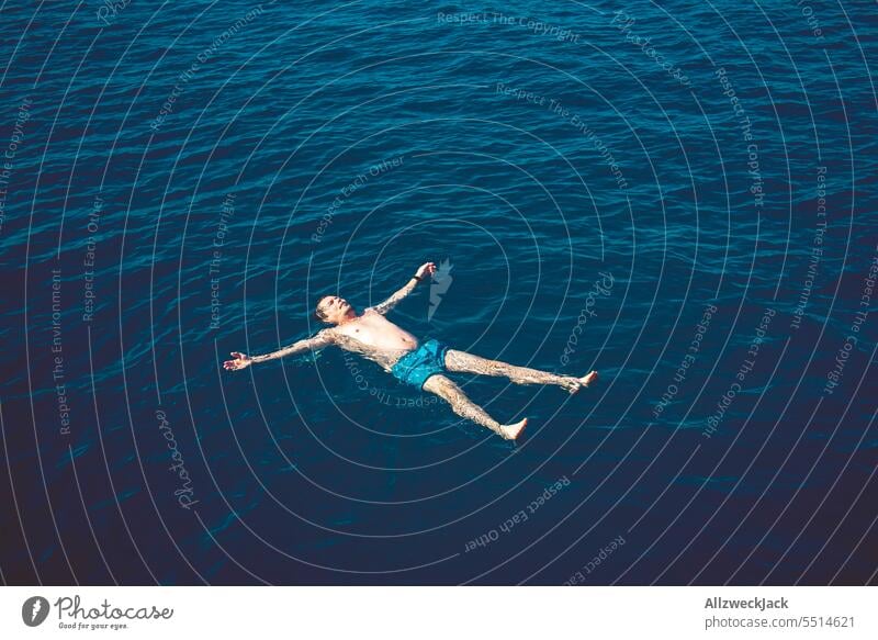 Middle aged man lying backwards in blue sea with arms and legs stretched out Ocean Oceans Water ocean Blue Swimming & Bathing bathe H2O Maritime drift Hover