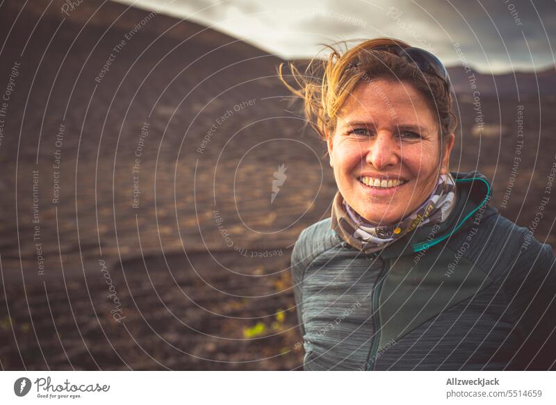 Portrait of smiling blonde middle aged woman in landscape with dark lava rocks Woman Middle aged woman Blonde blonde hair portrait pretty Adults naturally