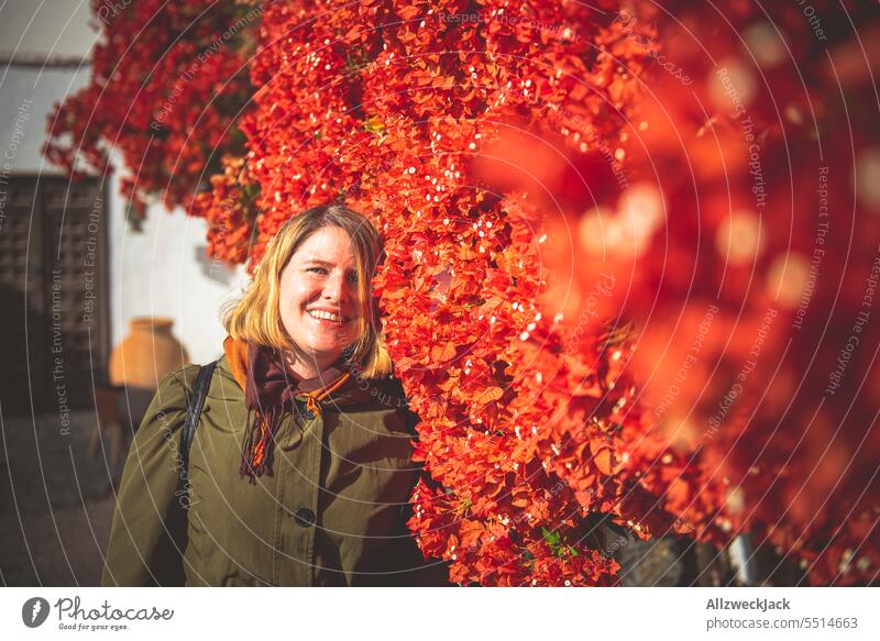 Portrait of blonde middle aged woman in front of wall full of red flowers Woman Middle aged woman portrait blossoms Blossoming Red Lanzarote Blonde blonde hair