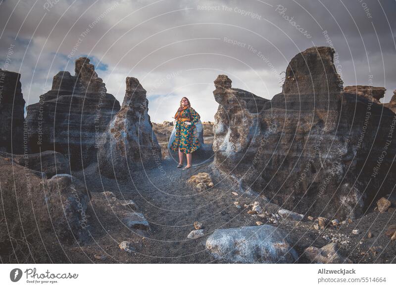 Middle aged woman with dress between rocks in front of cloudy sky Lanzarote posing Rock Nature outdoor ascent townspeople city people Clouds Sky