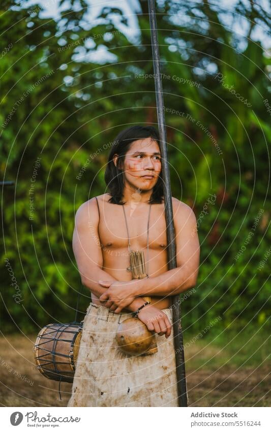 Tribal man with stick in tropical forest nature serious plant green naked torso woods exotic male ethnic young tree flora environment natural foliage summer