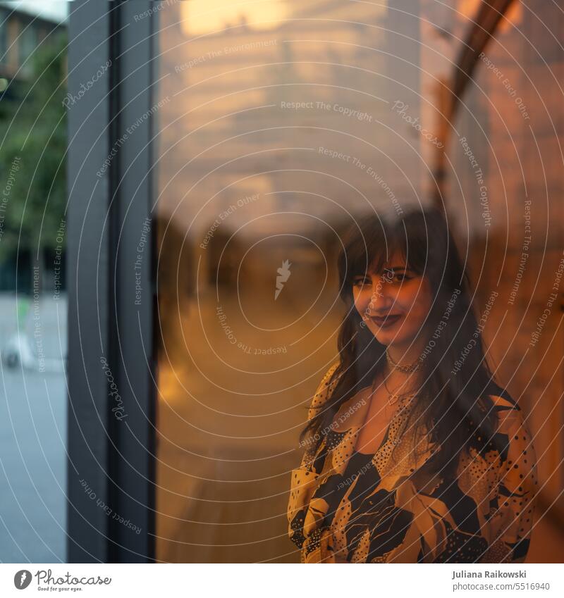 Young woman in the city behind a window Hip & trendy Looking street style street photography urban Town Lipstick Face Hair and hairstyles Elegant pretty