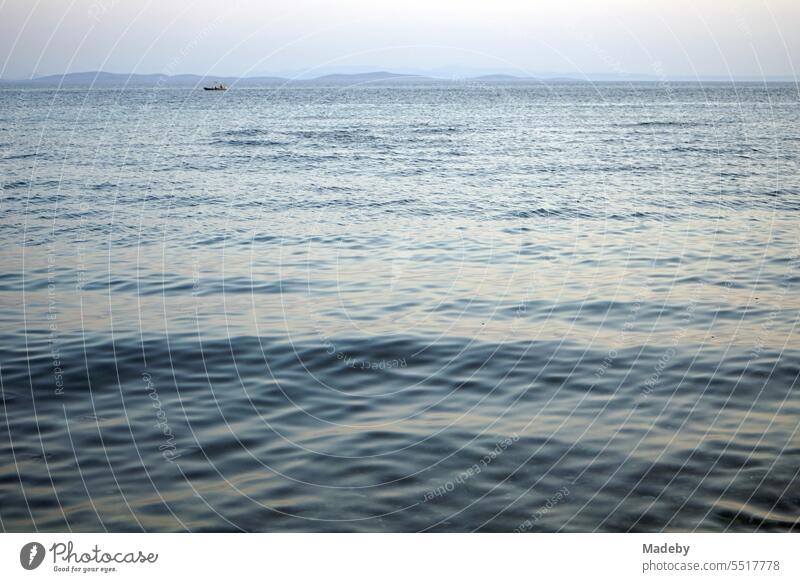 View from the beach in Altinoluk in the romantic light of the setting sun on the Gulf of Edremit on the Aegean Sea in the province of Balikesir in Turkey