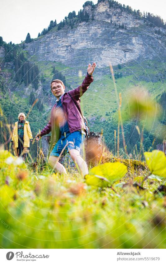 young couple with rain jackets hiking on a swiss alpine pasture Switzerland Swiss Alps Alpine pasture Meadow Nature Green Juicy juicy green Valley trees Wet