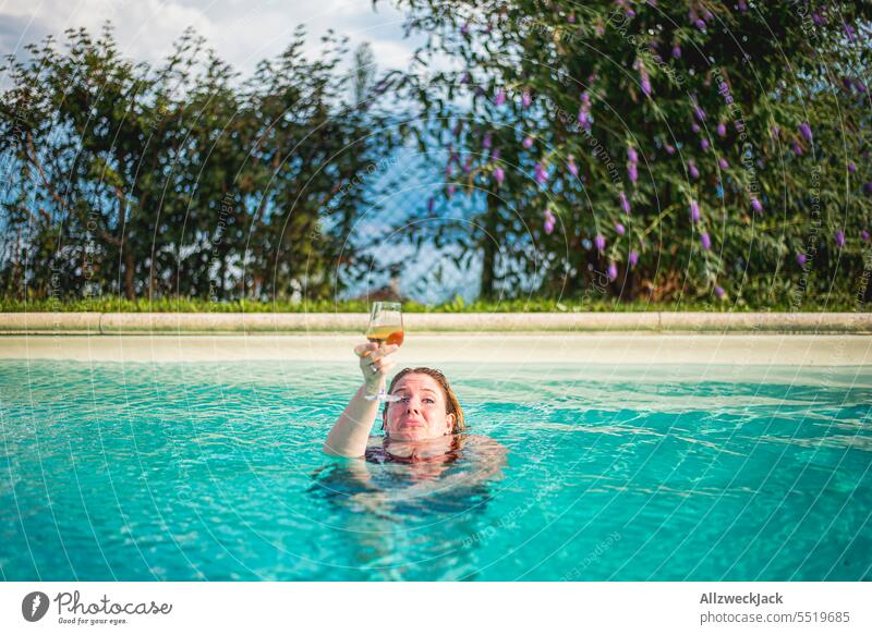 young woman in pool holds up glass of white wine while water is up to her neck Young woman Woman pretty Congenial Refreshment Cold drink White wine Vine Glass