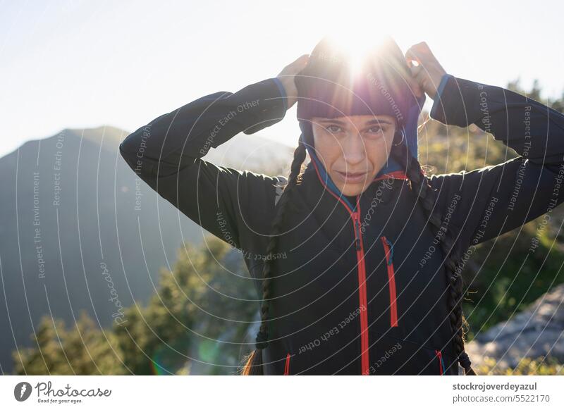 A young woman, mountaineer, sheltered by the cold at the top of a mountain, enjoys the landscape and the moment in nature person travel outdoors hiker female