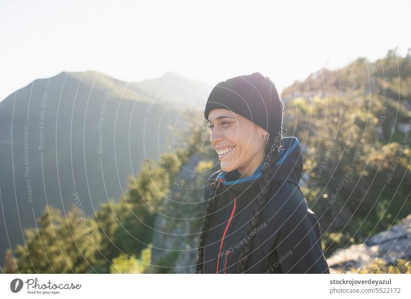 A young woman, mountaineer, sheltered by the cold at the top of a mountain, smile and enjoys the landscape and the moment in nature lifestyle female person