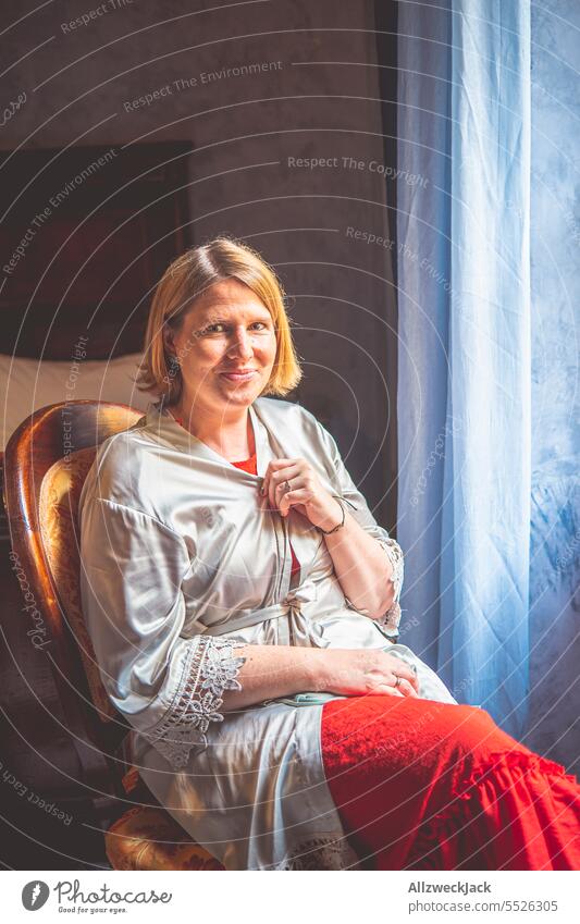 middle-aged blonde woman in a robe sits on a chair by the window Blonde blonde hair Woman Middle aged woman pretty Attractive Congenial timid Sit To enjoy