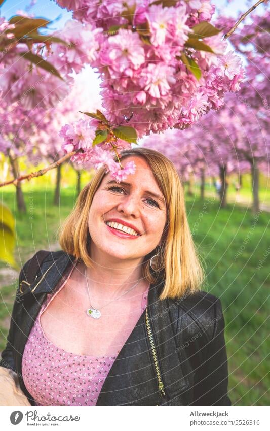 Portrait of smiling young blonde woman next to flowering cherry blossom branch portrait Woman Middle aged woman Young woman blonde hair blonde girl Blonde