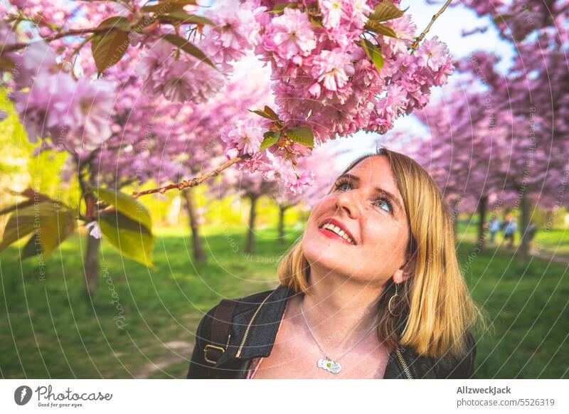 Portrait of smiling young blonde woman next to flowering cherry blossom branch portrait Woman Middle aged woman Young woman blonde hair blonde girl Blonde