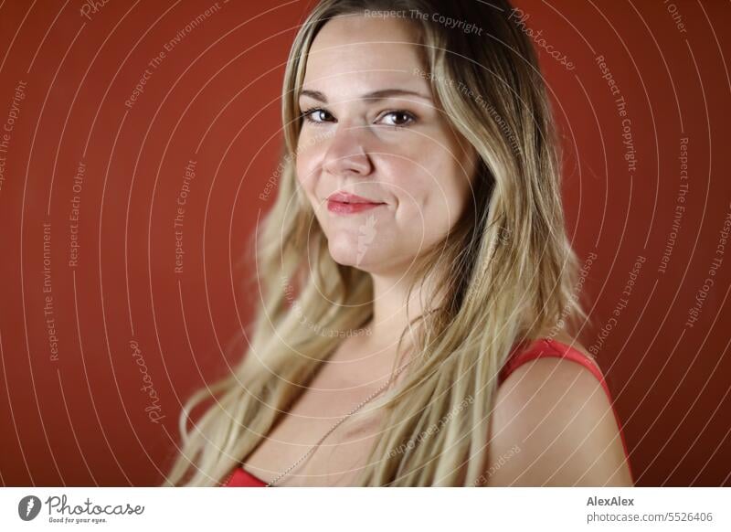 Portrait of blonde beautiful smiling woman in red dress in front of red wall Woman portrait Long-haired long hairs Face naturally pretty Authentic Attractive