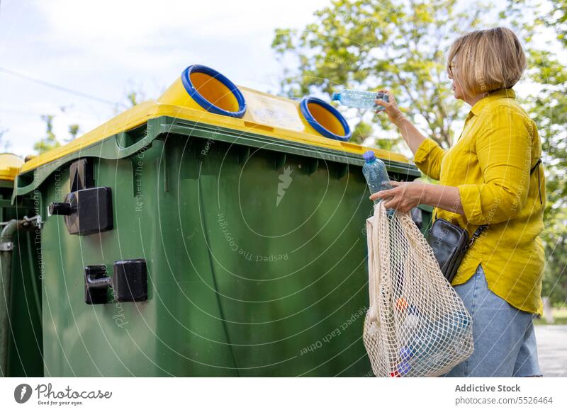 Woman throwing out trash in yellow bin recycle plastic garbage carry ecology problem casual rubbish daylight waste container reduce package utilize litter junk