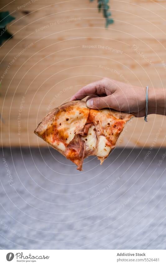 Unrecognizable person holding delicious pizza slice in hand in daylight baked tomato food piece tasty meal yummy fresh appetizing homemade italian leaf cuisine