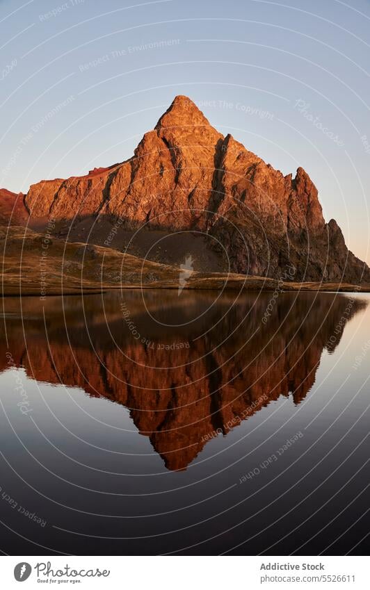 Calm lake surrounded by Anayet peak mountain pyrenees ridge stone rock slope twilight range rocky rough scenic landscape environment dusk hill sunset valley