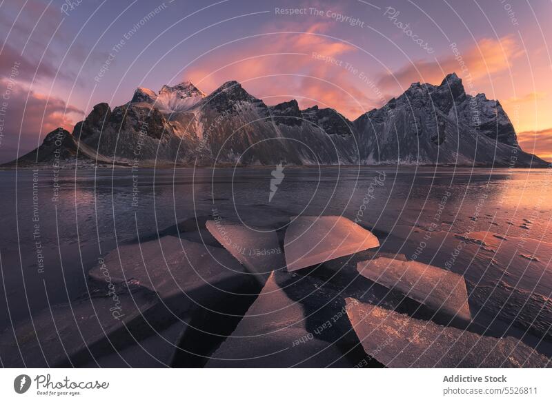 Ice pieces on black sand beach against mountains frozen ice winter snow stockness vestrahorn sunset scenery picturesque iceland cold evening sky cloudy scenic