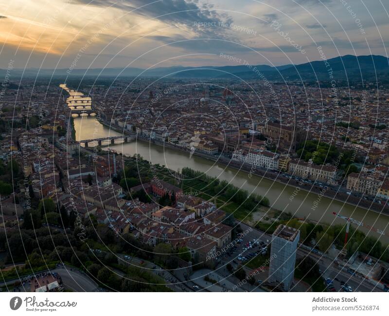 Drone view of cityscape with river in between and residential buildings sunset architecture sky bridge street exterior orange sundown roof district cloudy town