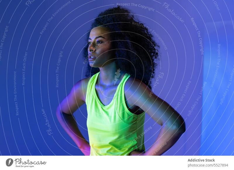 Black woman in headphones standing hand on waist portrait studio shot black sport fitness female sportswoman meloman sound activewear wellness sportswear young