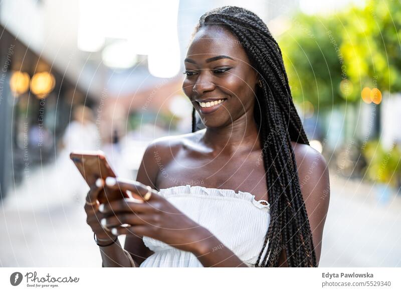 Portrait of an young woman using mobile phone in the city adult attractive beautiful black confidence confident cool female girl hairstyle leisure lifestyle