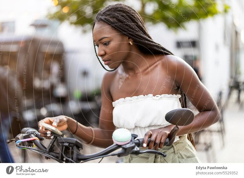 Portrait of an young woman with her bicycle in the city adult attractive beautiful black confidence confident cool female girl hairstyle leisure lifestyle