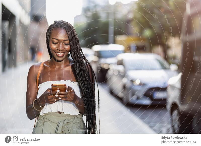 Portrait of an young woman using mobile phone in the city adult attractive beautiful black confidence confident cool female girl hairstyle leisure lifestyle