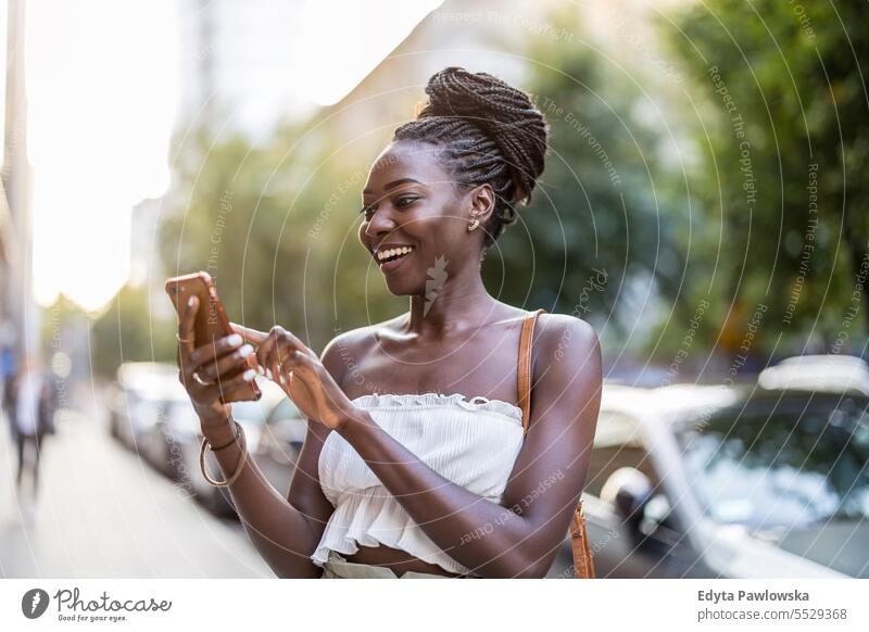 Portrait of an young woman using mobile phone in the city adult attractive beautiful black confidence confident cool female girl hairstyle leisure lifestyle