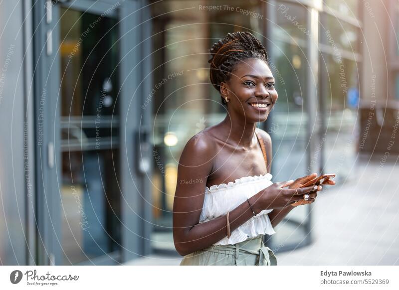 Portrait of an young woman using mobile phone in the city adult attractive beautiful black confidence confident cool female girl hairstyle leisure lifestyle