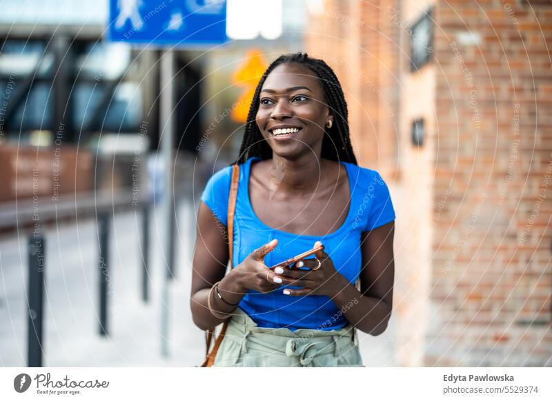 Portrait of an young woman using mobile phone in the city adult attractive beautiful black confidence confident cool female girl hairstyle leisure lifestyle