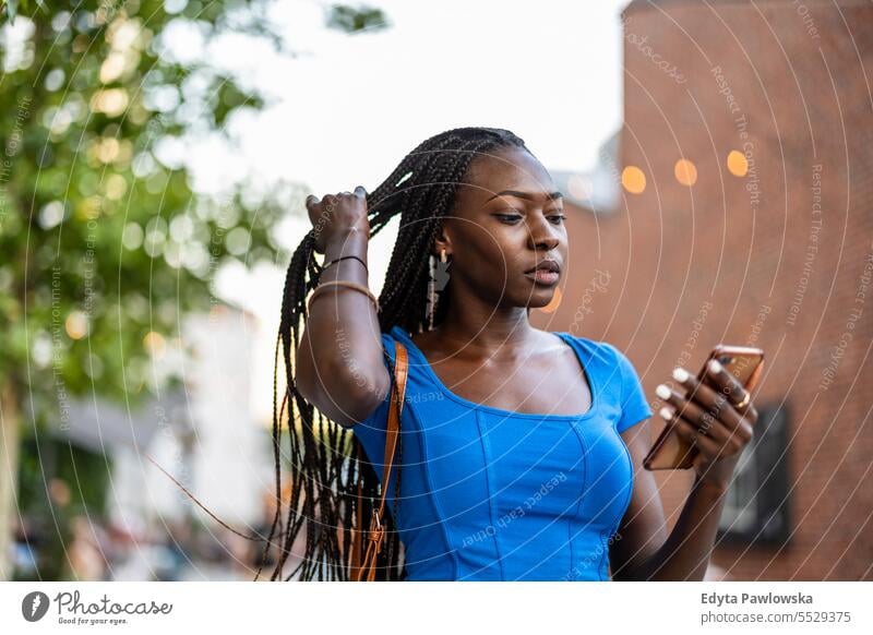 Portrait of an young woman using mobile phone in the city adult attractive beautiful black confidence confident cool female girl hairstyle leisure lifestyle