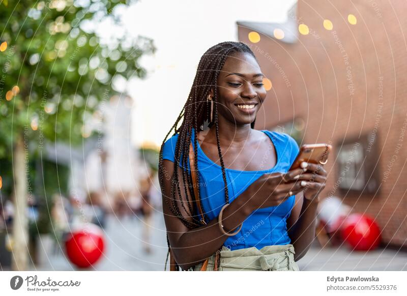 Portrait of an young woman using mobile phone in the city adult attractive beautiful black confidence confident cool female girl hairstyle leisure lifestyle