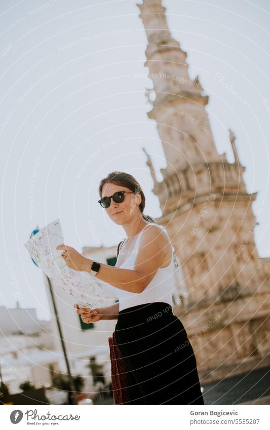 Female tourist with city map by the Saint Oronzo statue in Ostuni, Italy woman young female direction navigation ostuni sky town brindisi tourism oronzo italy